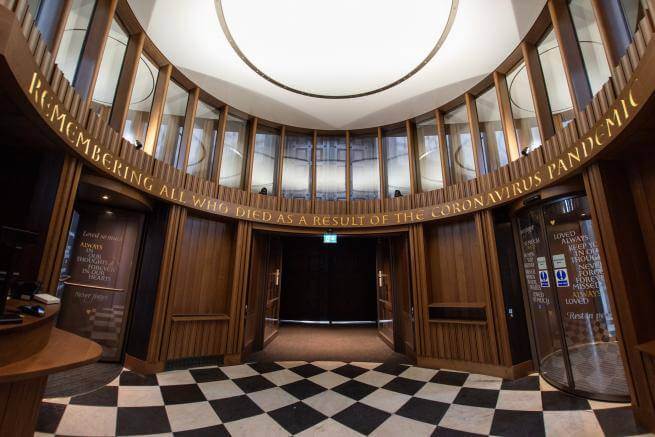 The wooden elliptical interior of the Remember Me inner portico is shown reading 'Remembering all who died as a result of the coronavirus pandemic'