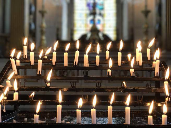 A series of lit candles on the candle stand in the cathedral