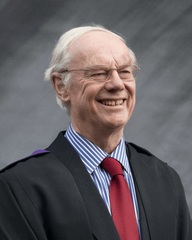 A grey-haired white man with glasses wearing academic robes over a suit and tie.