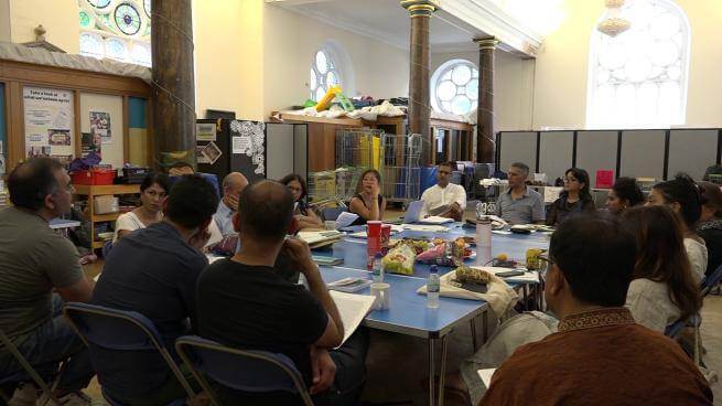 A community engagement workshop, where a group discussion is happening around a table.