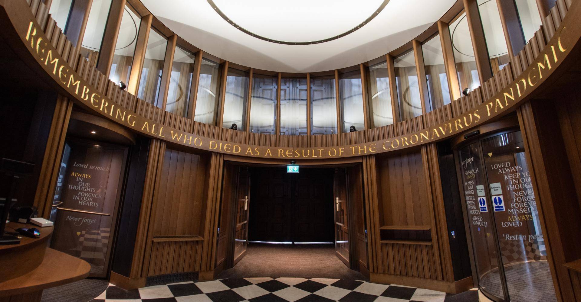 The wooden elliptical interior of the Remember Me inner portico is shown reading 'Remembering all who died as a result of the coronavirus pandemic'