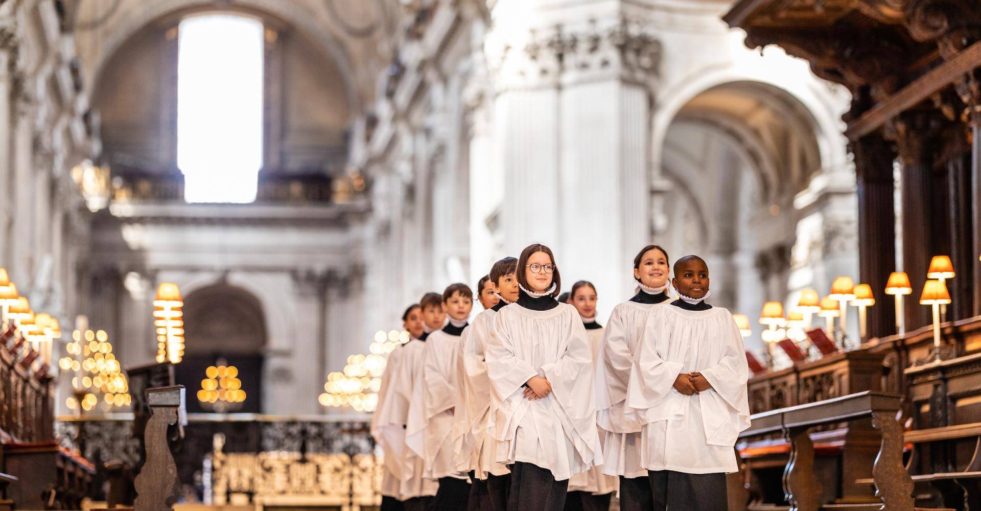 Girl and boy choristers in robes walking in the quire