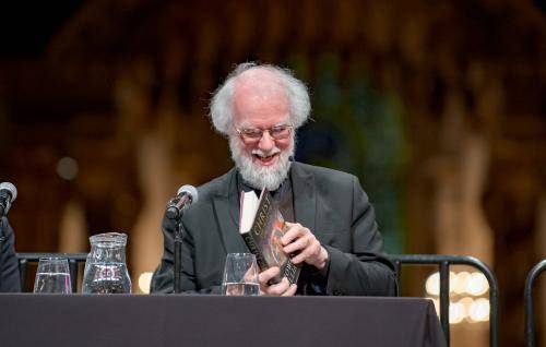 Rowan Williams smiling as he leafs through his book at an event at St Paul's Cathedral