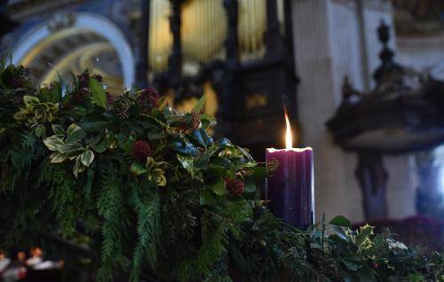 An image of a lit purple candle in the Advent wreath with the organ pipes in the background