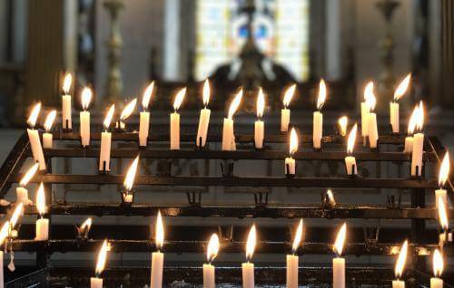 A series of lit candles on the candle stand in the cathedral