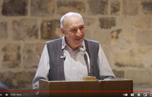 Bob Gilbert, a white man with short grey hair, wearing a white shirt and a grey waistcoat, talks in the Wren Suite at St Paul's