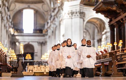 Girl and boy choristers in robes walking in the quire