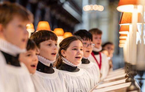 Girl and boy choristers in robes singing in the quire