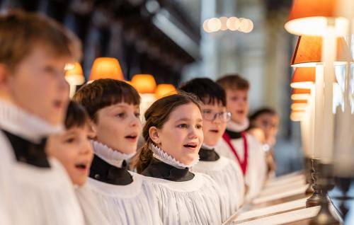 Girl and boy choristers in robes singing in the quire