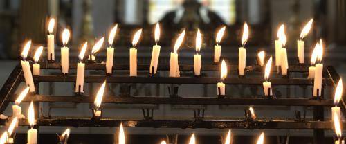 A series of lit candles on the candle stand in the cathedral